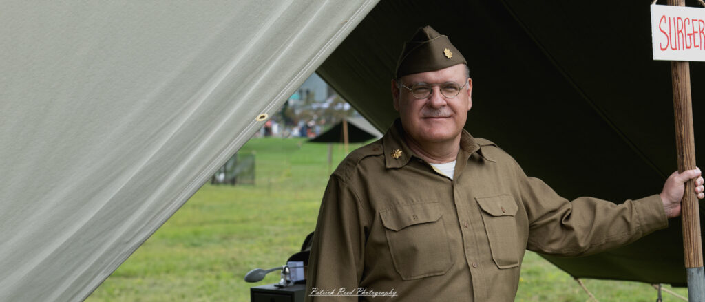 An army surgeon in uniform standing in front of his tent, exuding professionalism and determination. His attire reflects the military context, highlighting his commitment to providing medical care in challenging conditions during wartime.